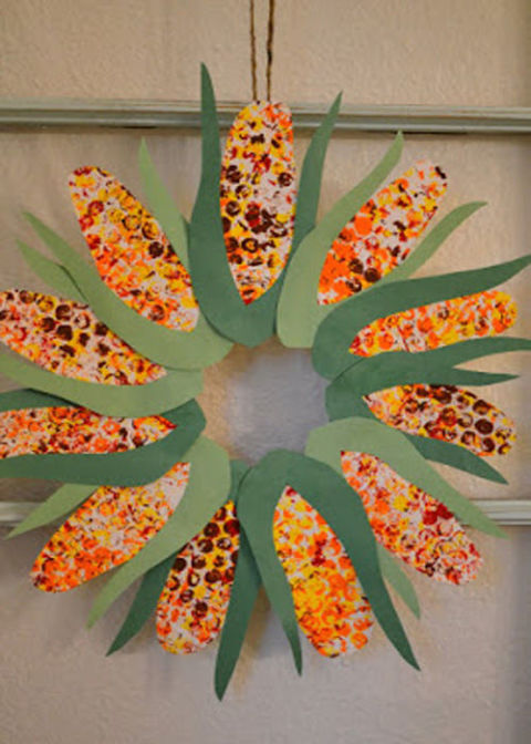 Cut out construction paper corn cobs and roll them with different colors for a farm-style wreath. 
Get the tutorial at Real Life, One Day at a Time.
