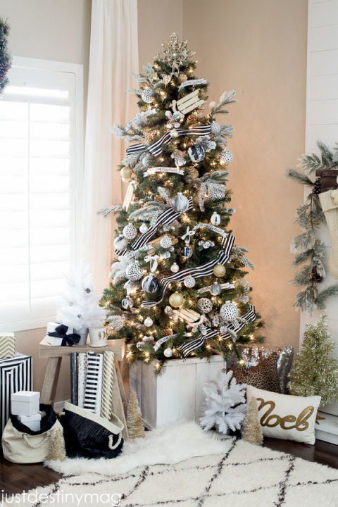 Black-and-white striped ribbon wraps around a Christmas tree that's adorned with flocked branches and faux marble ornaments.<br>Get the tutorial at Just Destiny.