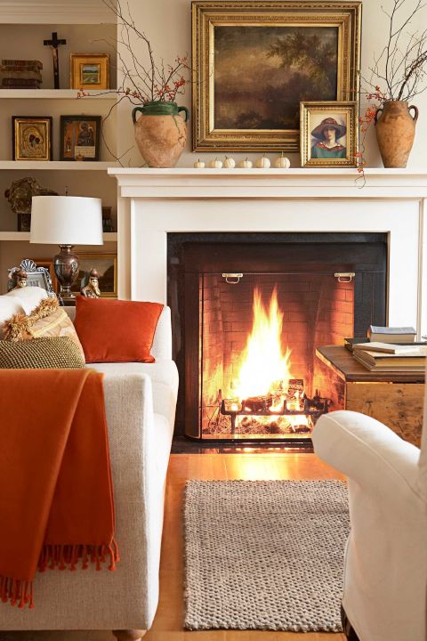 A roaring fire takes center stage in the living room of this New Hampshire home, furnished with a nubby cream sofa and white slipcovered chairs, both from Crate &amp; Barrel.
