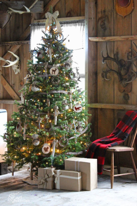 Placed in front of her aunt's vintage enamel wood stove, blogger Virginia Fynes's rustic tree is decorated with birch sticks, glittered acorns and wreaths, hoop art, and feathers. <br>Get the tutorial at Fynes Designs.