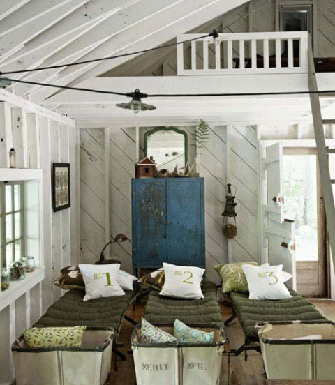 A row of antique wood cots and vintage hampers fill this kids' cabin with plenty of opportunities and room to host sleepovers for friends. Canvas number-print pillows were handmade.