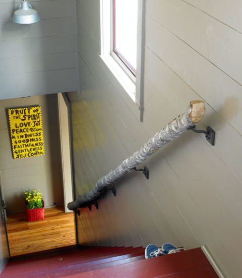 This handrail—made from an oak log cut on the property—lends a woodsy touch to the stairs leading down to the game room. The folk-art sign was bought at a local shop. 