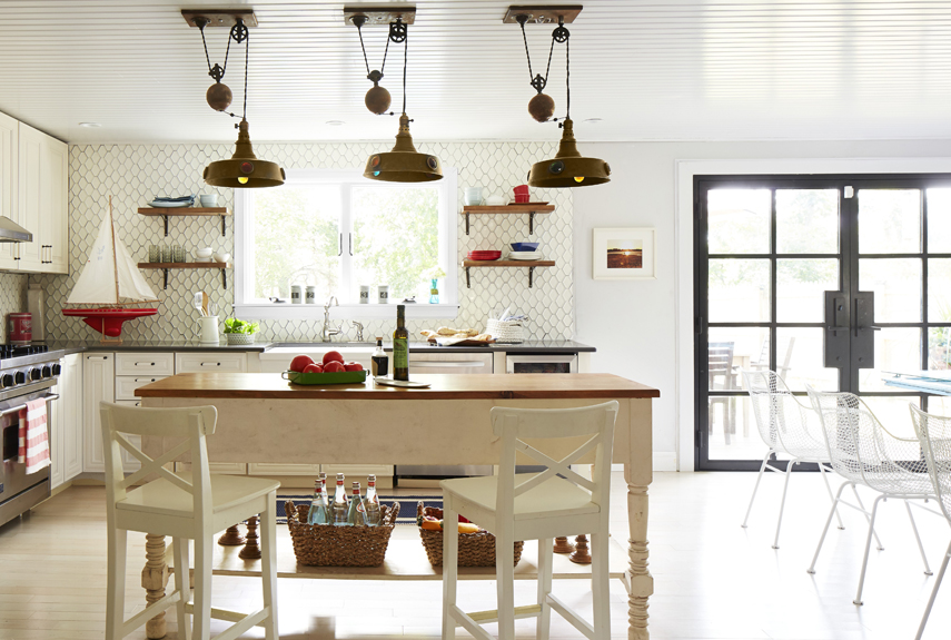 With still-functioning pulleys, these industrial and salvaged light fixtures (once used in a billiard hall) make for eye-catching (and hardworking) task lighting above the island in this coastal cottage.